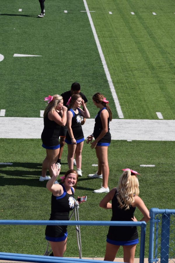 Recently injured cheerleader, Brandi Elmore, smiles and waves to the camera from the sidelines. This past Saturday, you could spot Brandi in a boot and crutches on the sidelines morally supporting her fellow squad members.