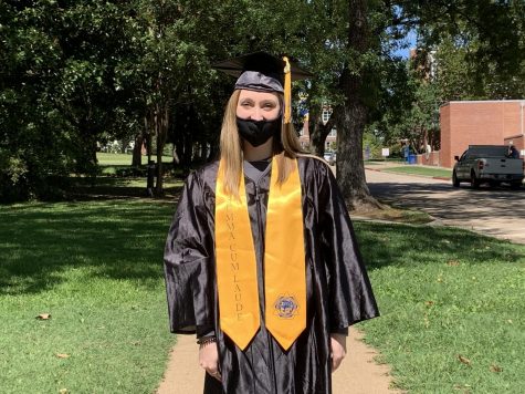 Jade Claxton, junior nursing student, models graduation regalia outside of the SE bookstore. Graduates can order their caps and gowns now.